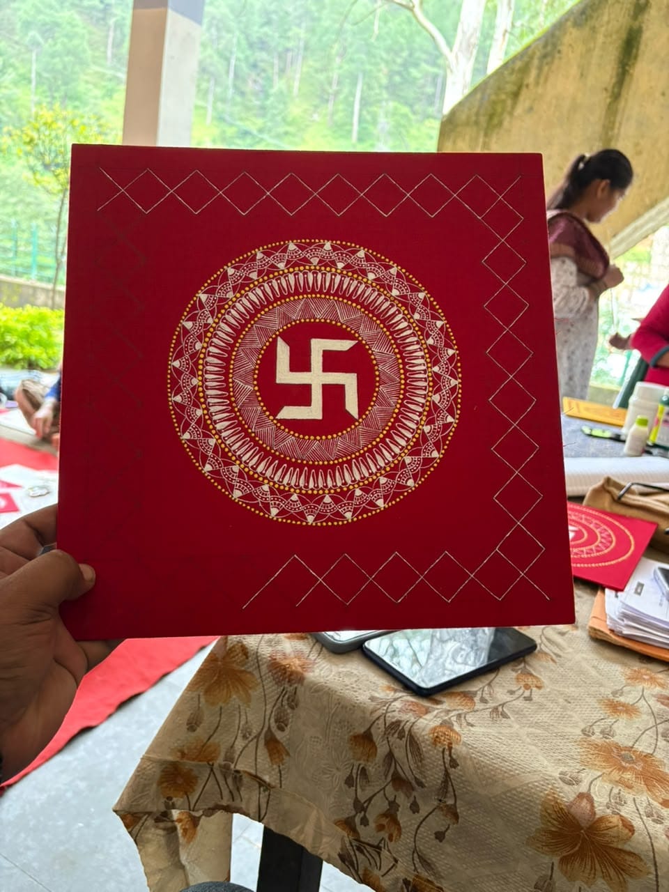 A red Aipan artwork held before framing