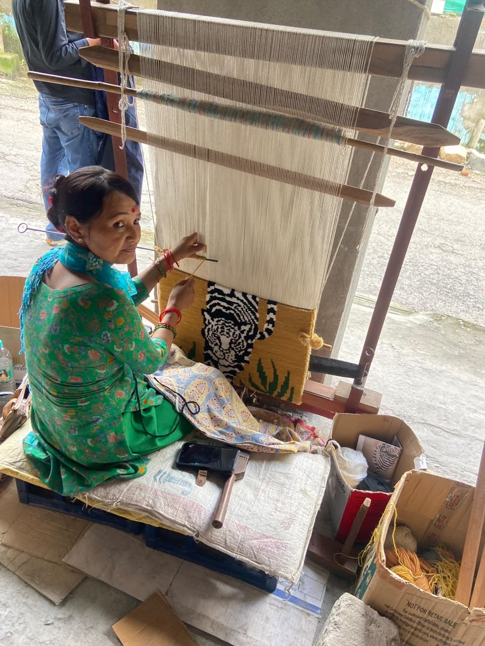 An artisan working at a loom on a tiger design